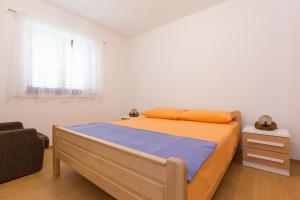 a bedroom with a bed and a chair and a window at Apartment Polugic in Punat