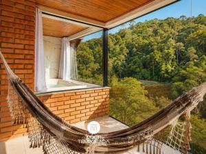 a hammock in a room with a view of the forest at Pousada Dona Teresinha com Piscina Aquecida - São Bonifácio/SC in São Bonifácio