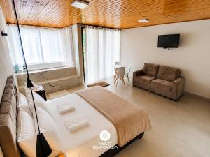 a bedroom with a bed and a couch and a television at Pousada Dona Teresinha com Piscina Aquecida - São Bonifácio/SC in São Bonifácio