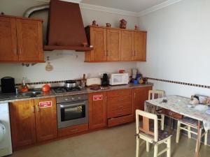 a kitchen with wooden cabinets and a table with a microwave at Casa Bia Olívia in Albernoa