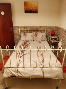 a metal bed in a bedroom with a brick wall at Casa Bia Olívia in Albernoa