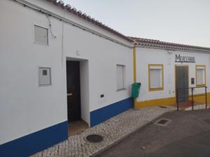 a white and blue building with a parking lot at Casa Bia Olívia in Albernoa