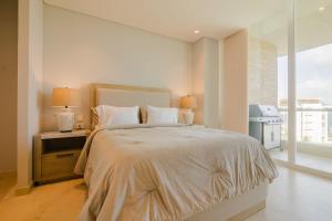 a white bedroom with a large bed with two lamps at Modern apt with 2 BR BBQ and views in Cartagena de Indias