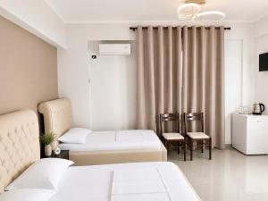 a hotel room with two beds and two chairs at Hotel Albsin in Vlorë