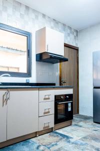a kitchen with white cabinets and a black refrigerator at Villas HouN Assinie in Mafia