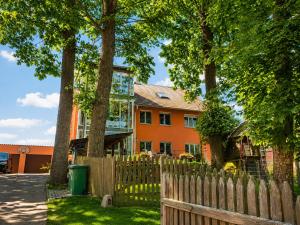 an orange house with a wooden fence and trees at Ferienwohnung Schaftnach Rednitzblick nähe Messe in Schwabach