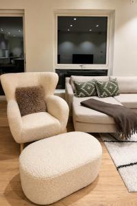 a living room with two chairs and a couch and a tv at The View - 4BR Central Voss - The Voss Collection in Vossevangen