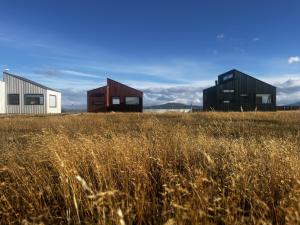 three houses in a field with a field of grass at Cabaña Julián Elias Verde in Puerto Natales