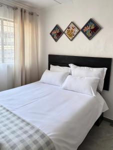a bedroom with a white bed with four pictures on the wall at The Tiny House - Solwezi in Solwezi