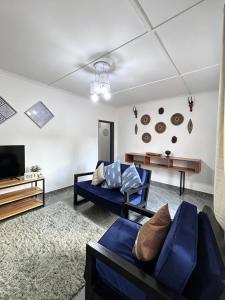 a living room with two blue couches and a tv at The Tiny House - Solwezi in Solwezi