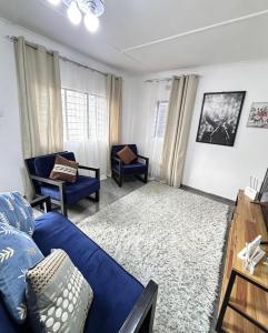 a living room with a blue couch and chairs at The Tiny House - Solwezi in Solwezi