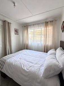 a white bed in a bedroom with a window at The Tiny House - Solwezi in Solwezi
