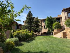 a yard of a house with a green lawn at Hotel Villa de Alquézar in Alquézar