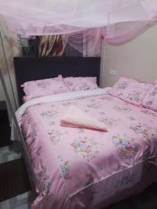 a pink bed with a pink comforter and pillows at The John's Park in Mwanza