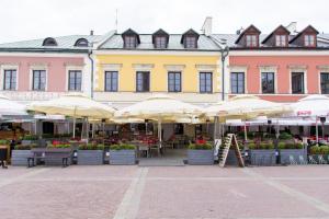 a building with tables and umbrellas in a courtyard at Pokoje na Starówce in Zamość