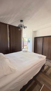a large white bed in a bedroom with a chandelier at Saymon apartment Trpejca in Ohrid