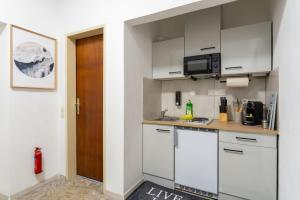 a small kitchen with white cabinets and a door at Quiet - 4 Guests - Self Check-in - Netflix - 35m2 in Leoben +19 photos