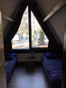 a attic room with two beds and two windows at Vakantiepark Vosseven 77 in Stramproy