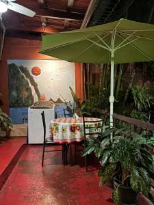 a table with a green umbrella in a room at Charly's Place in Alajuela