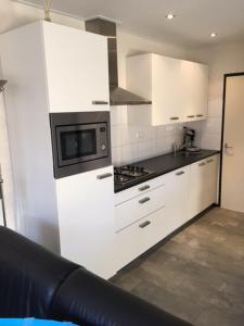 a kitchen with white cabinets and a microwave at Vakantiepark Vosseven 77 in Stramproy
