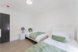 two beds in a bedroom with white walls at 4 Bedroom modern apartment in Birkenhead +4 photos