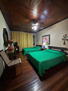 two green beds in a room with wooden floors at Charly's Place in Alajuela