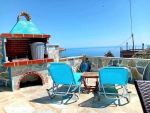 two chairs and a table on a patio with a fireplace at Tsonos Home in Keramídhion