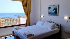 una camera da letto con un letto e un balcone con vista sull'oceano di Olympos Studios ad Amoopi