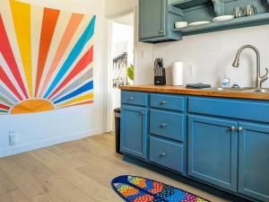 a kitchen with blue cabinets and a painting on the wall at Pet-Friendly Near Zion - Hot Tub Downtown Kanab in Kanab
