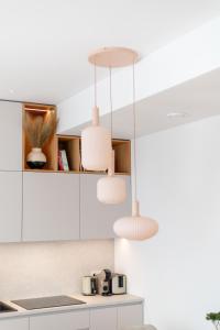 a kitchen with white cabinets and two pendant lights at Unique apartment with all comforts and sauna in Otepää