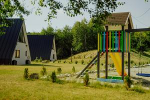ein Spielplatz mit Rutsche in einem Hof mit einem Haus in der Unterkunft Wild Hill Frames in Holbav