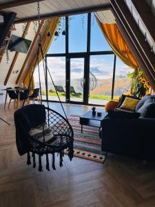 ein Wohnzimmer mit Schaukel und einem großen Fenster in der Unterkunft Wild Hill Frames in Holbav