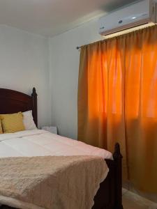 a bedroom with a bed and an orange curtain at Gasakam in San Pedro Sula