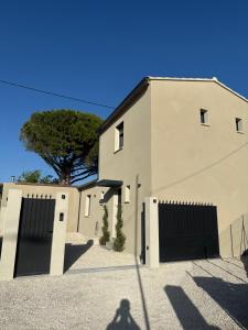 a white house with two garage doors and a tree at La villa Bern in Sorgues