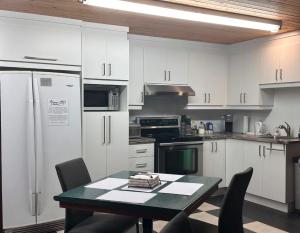 a kitchen with white cabinets and a table with chairs at Hôtel Auberge St-Félicien in Saint-Félicien +40 photos