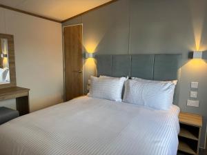 a bedroom with a large bed with white sheets and pillows at Luxury lodge Henley in Cherry Burton