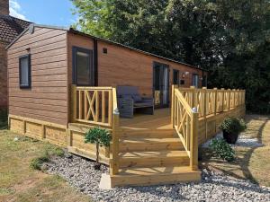a large wooden cabin with a wooden deck at Luxury lodge Henley in Cherry Burton