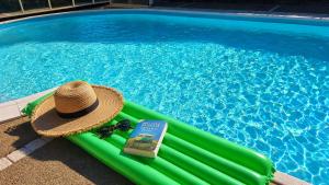 a hat and a book sitting on a raft next to a swimming pool at Gite de charme avec jaccuzzi privé in Coëx