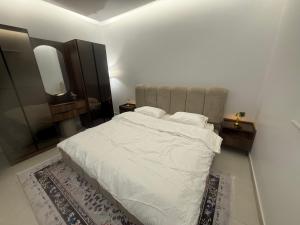 a bedroom with a white bed with two night stands and a mirror at Levin in Al Majma'ah