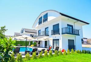 a white house with a swimming pool and chairs at ViLLA ANGEL AHMET HASAN in Belek