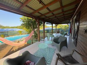 a patio with chairs and a hammock and a pool at Maison créole avec piscine et accès à la rivière in Lamentin