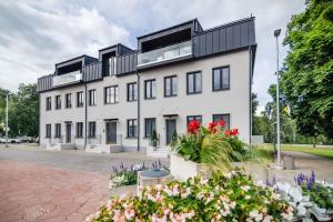 a large white building with black windows and flowers at Luxorious Japandi design apartment in Otepää