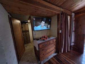 a living room with a tv and a dresser in a room at Casa Refugio del Amanecer en Baños de Agua Santa in Lligua