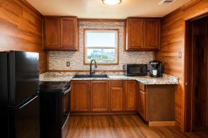 a kitchen with wooden cabinets and a black refrigerator at The Mint Motel in Arlington