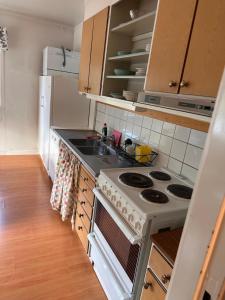 a kitchen with a stove and a sink and a refrigerator at Härjulfs hus in Lillhärdal