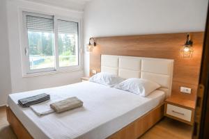 a bedroom with a large white bed with a wooden headboard at Beach Walk Apartments in Ulcinj