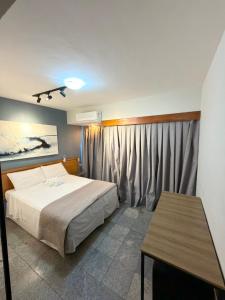 a bedroom with a bed and a table in it at Flat em natal beira mar in Natal