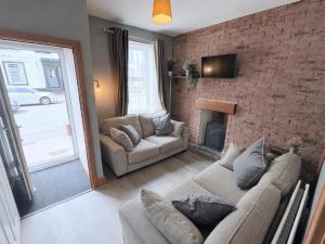 a living room with two couches and a brick wall at The Oaks Cottage in Penrith