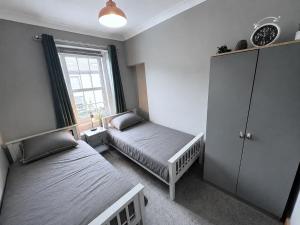 a small bedroom with two beds and a window at The Oaks Cottage in Penrith