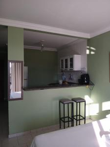 a kitchen with two bar stools and a counter at Paradise Hostel e Suítes in Itatiaia